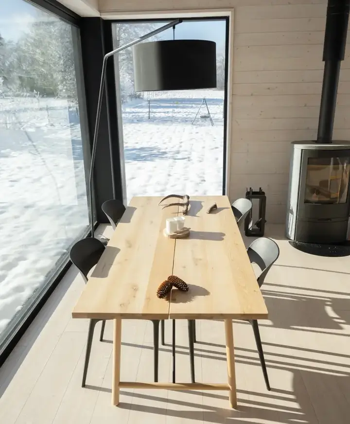 Pièce de vie lumineuse de Metsä avec table en bois et poêle